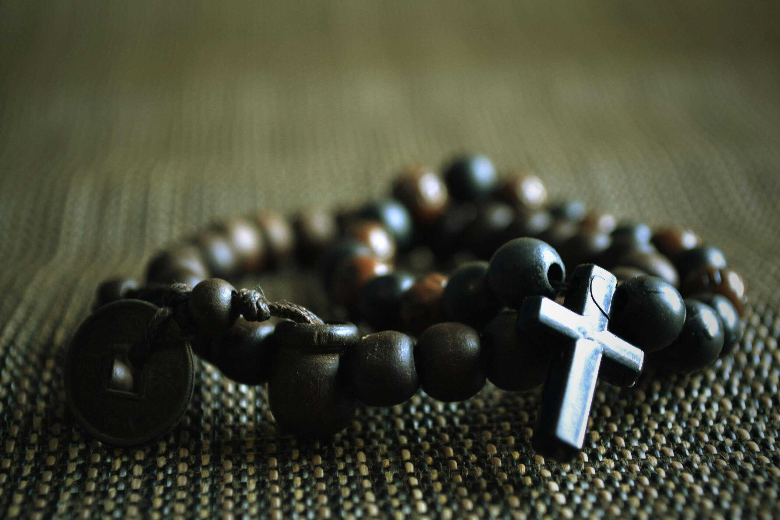 Detailed image of a wooden rosary with a cross on textured fabric, symbolizing faith.